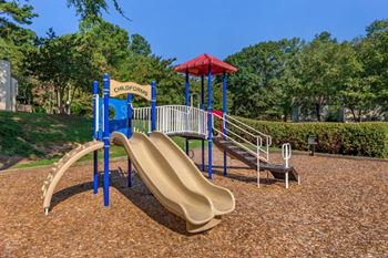 Colorful playground  on mulch with treeline in the background